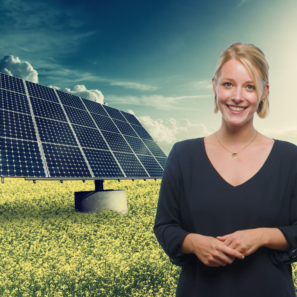 Eine lächelnde Frau vor einem großen Solarpanel in einem Feld